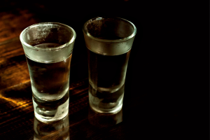 Dwa kieliszki alkoholu wysokoprocentowego stojące obok siebie na stole- ilustracja do artykułu o współuzależnieniu